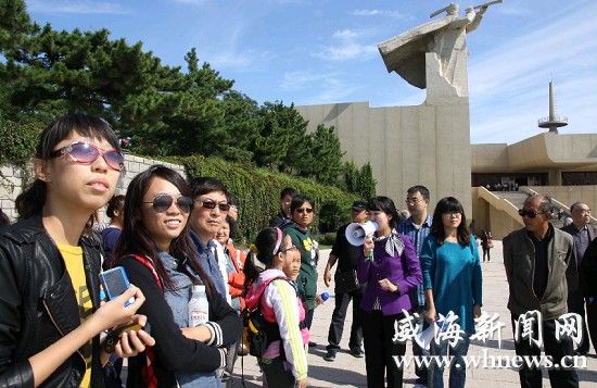10月2日上午，记者（讲解员右侧持喇叭者）在刘公岛景区体验讲解员的生活。（记者 于启波 摄） 