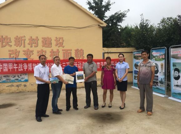 工作人员向乳山市崖子镇张格庄村书记李振孟赠送甲午历史书籍